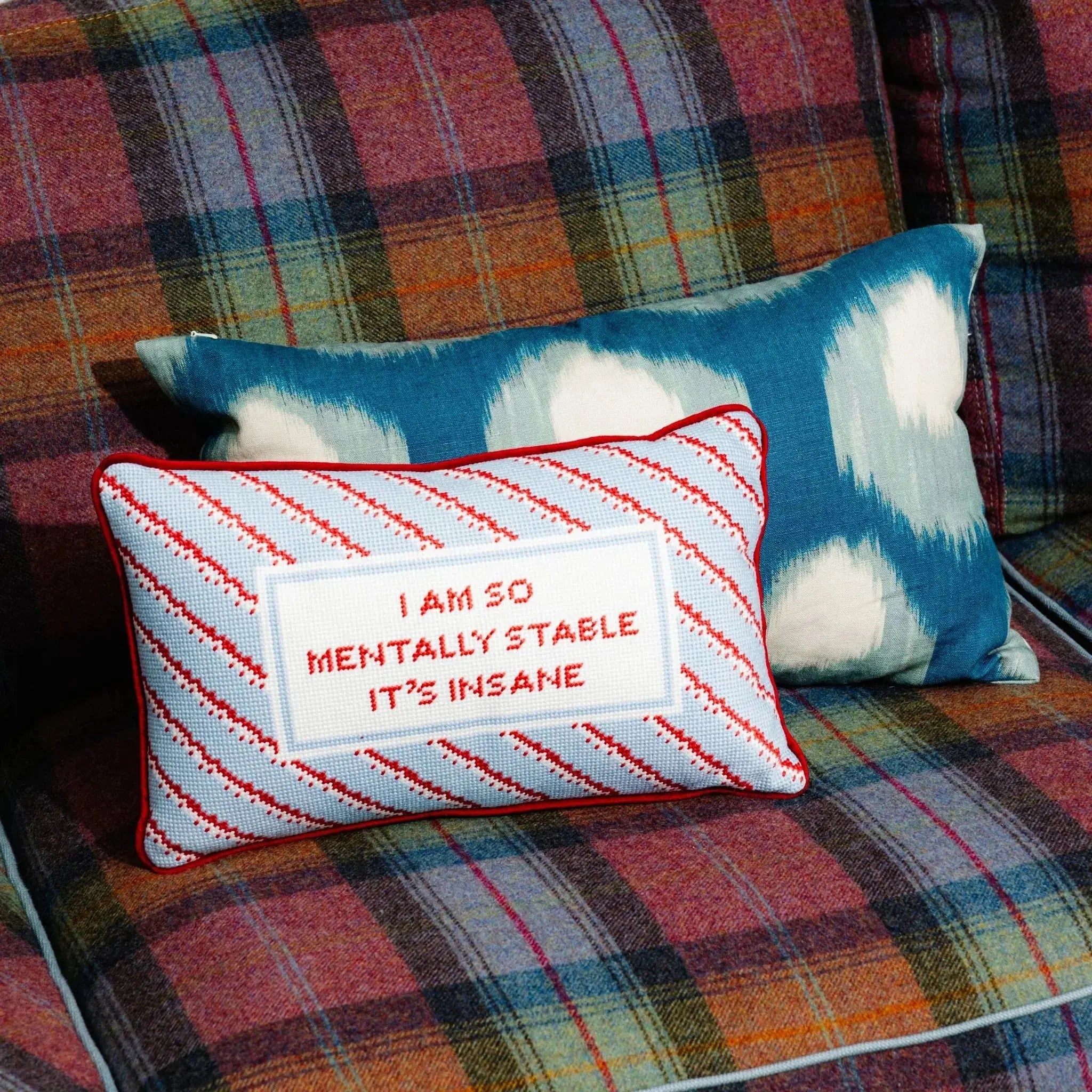 Decorative pillow with text on a plaid couch