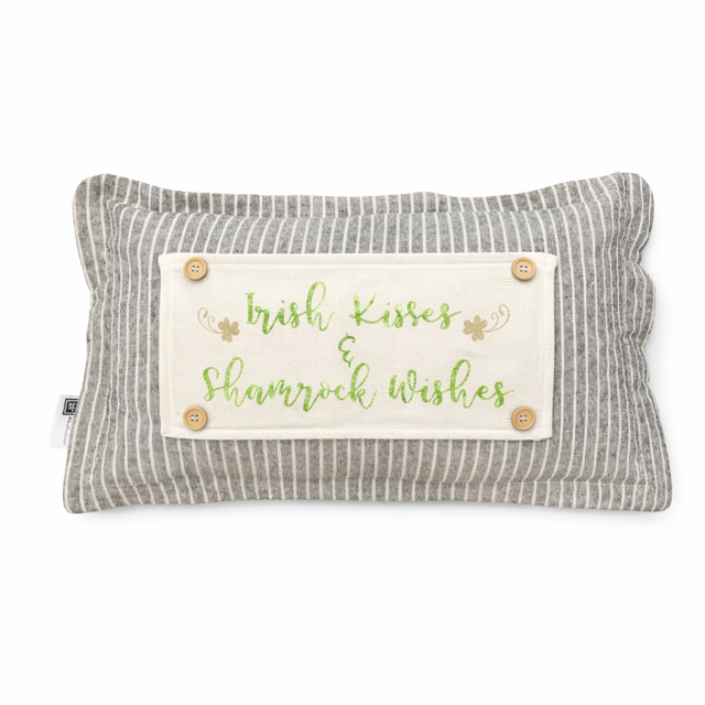 A rectangular striped lumbar pillow in gray and white with a cream patch that reads 'Irish Kisses & Shamrock Wishes' in green script, decorated with small shamrock motifs and four wooden buttons.