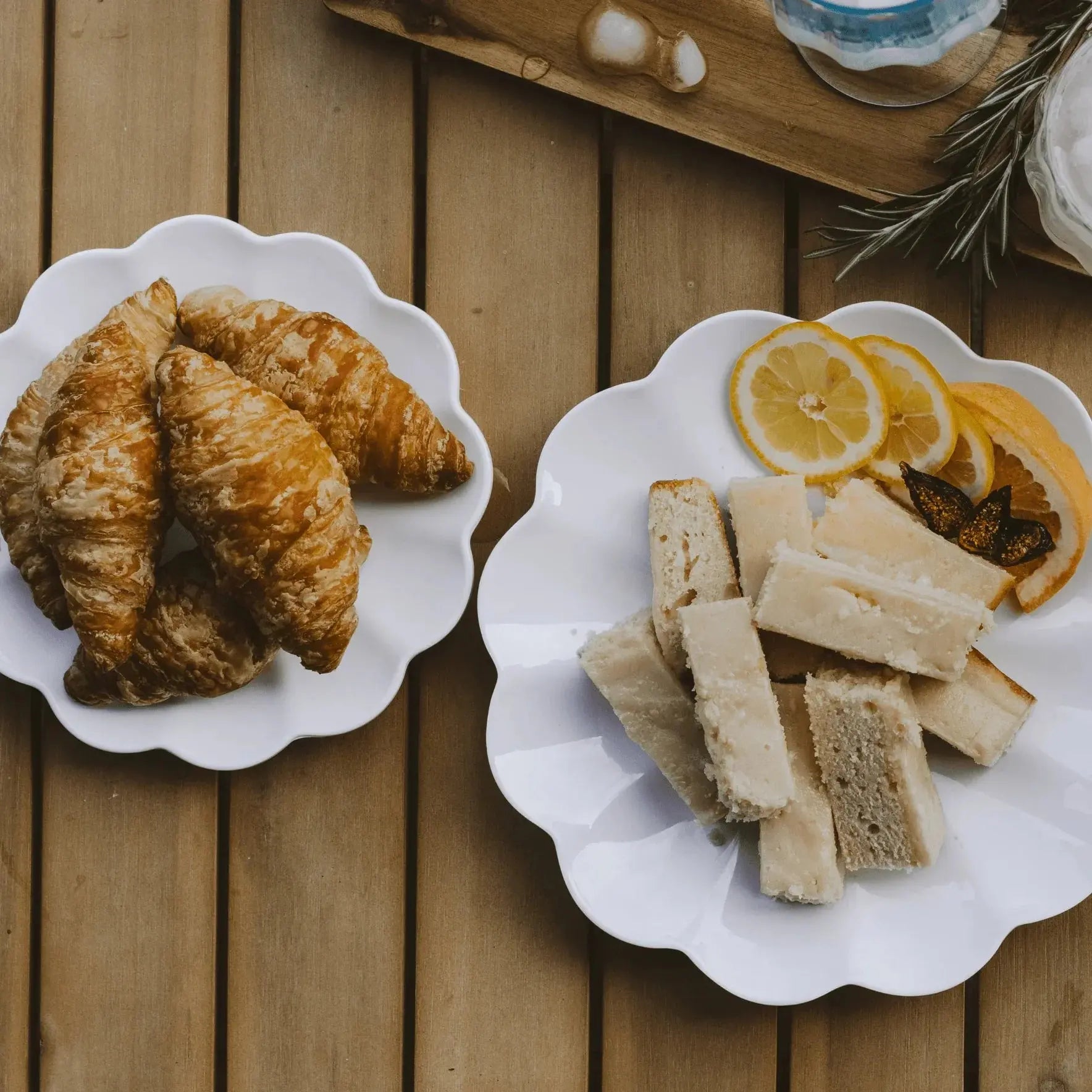 Cozy farmhouse-style breakfast with croissants, lemon slices, and buttered bread on white scalloped plates