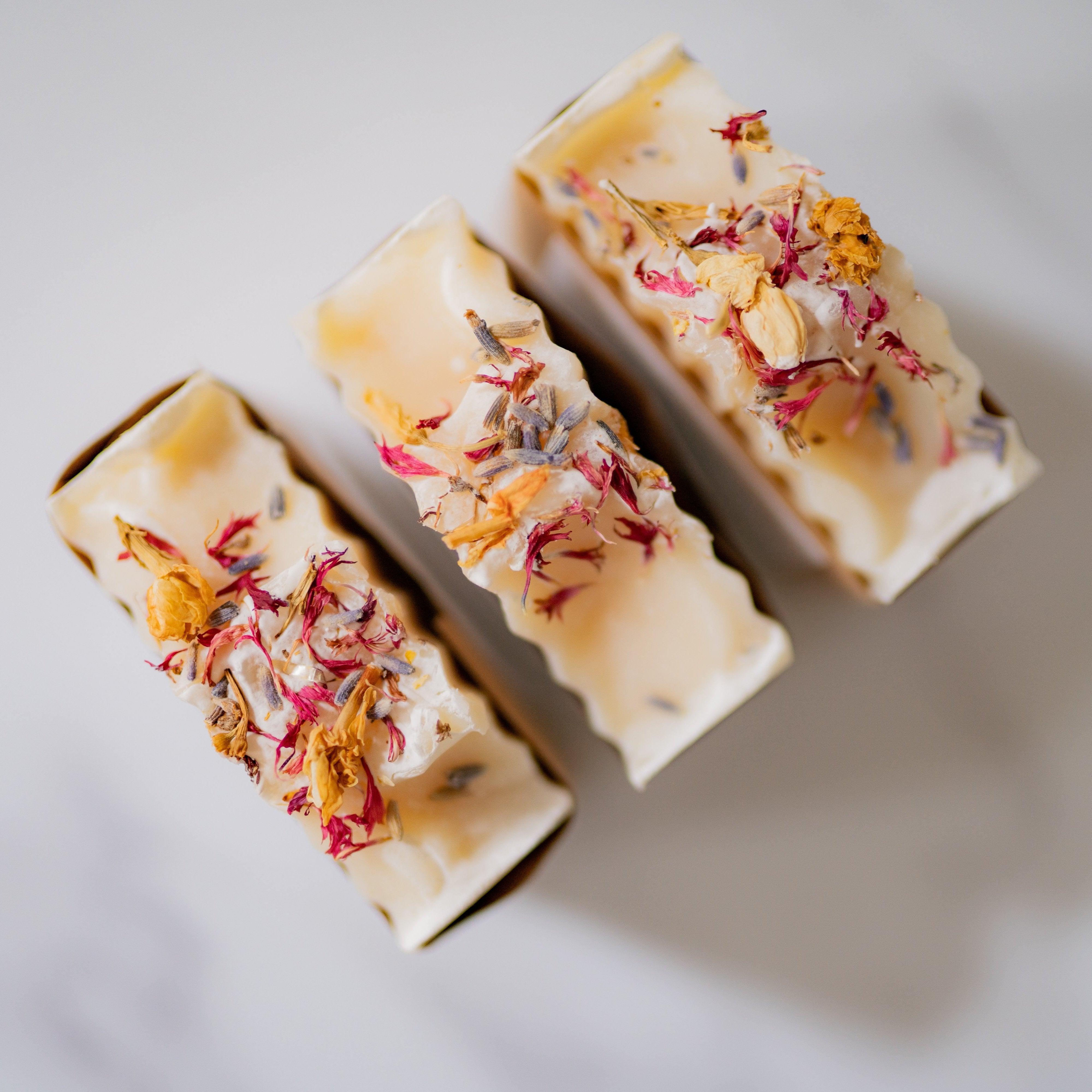 Three bars of soap with floral toppings on a light background