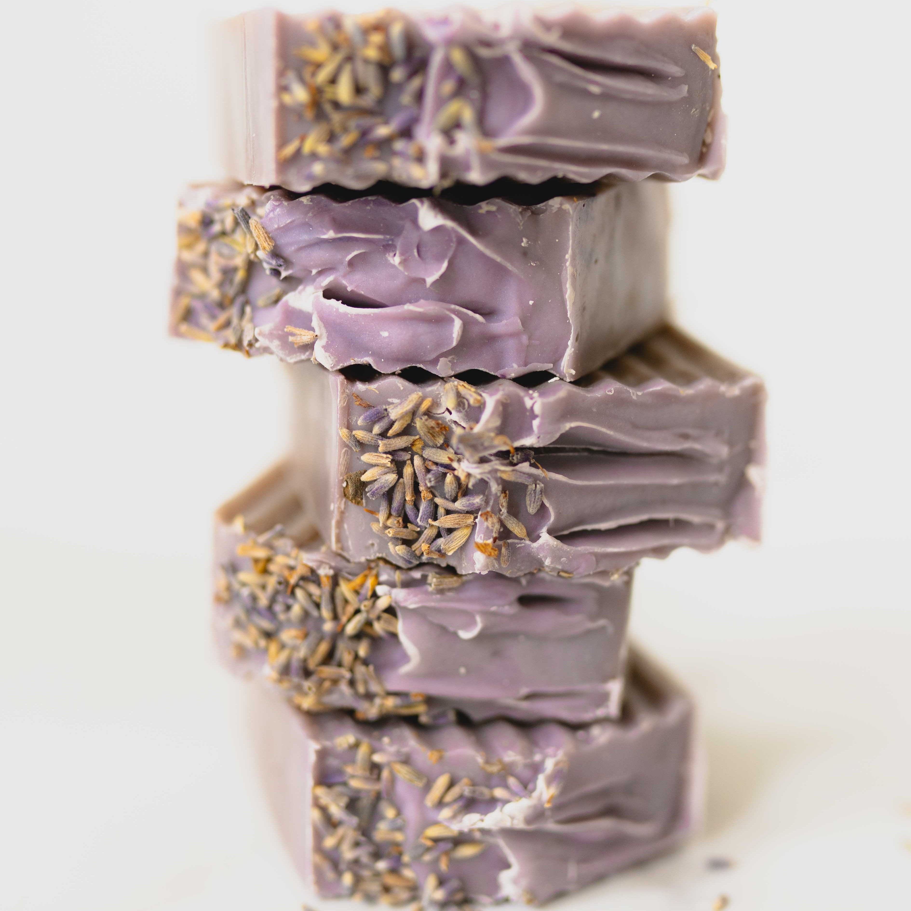 Stack of purple soap bars with lavender flowers on a white background