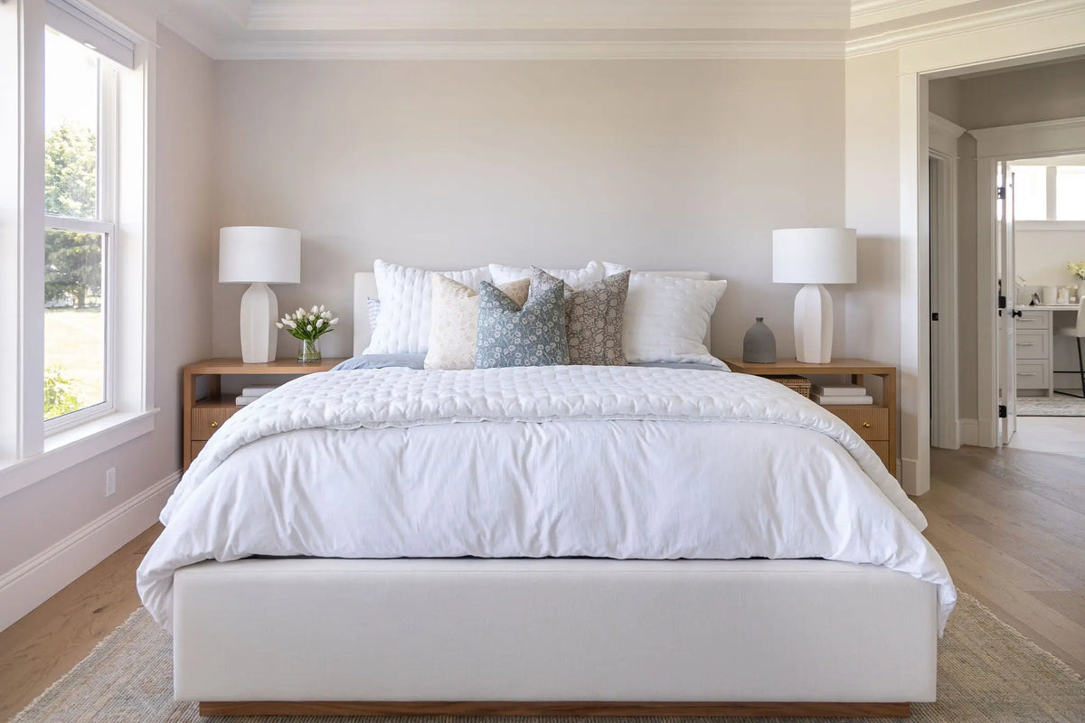 Neatly made bed with white bedding in a bright bedroom