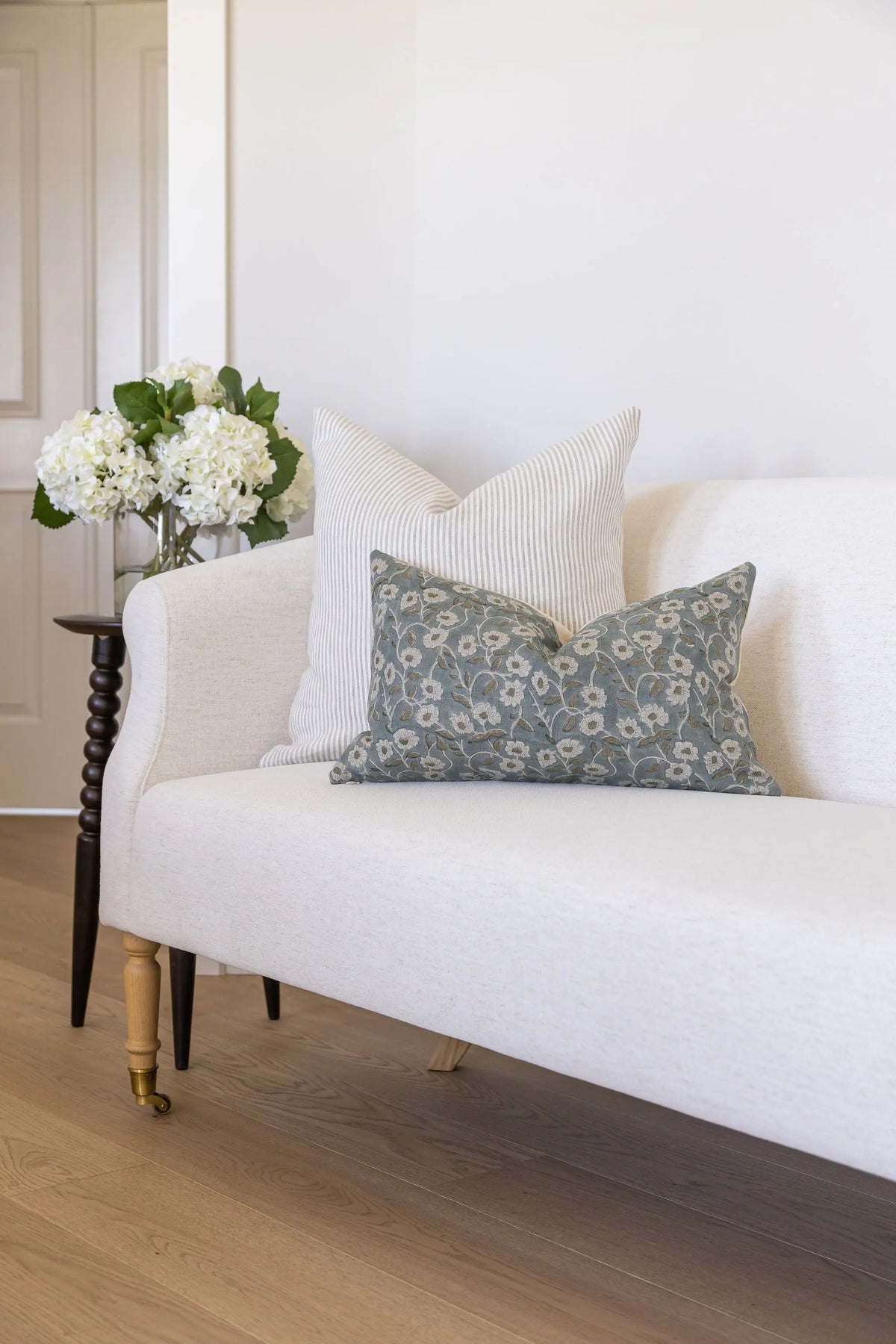 White sofa with decorative pillows and a small table with flowers in a room.