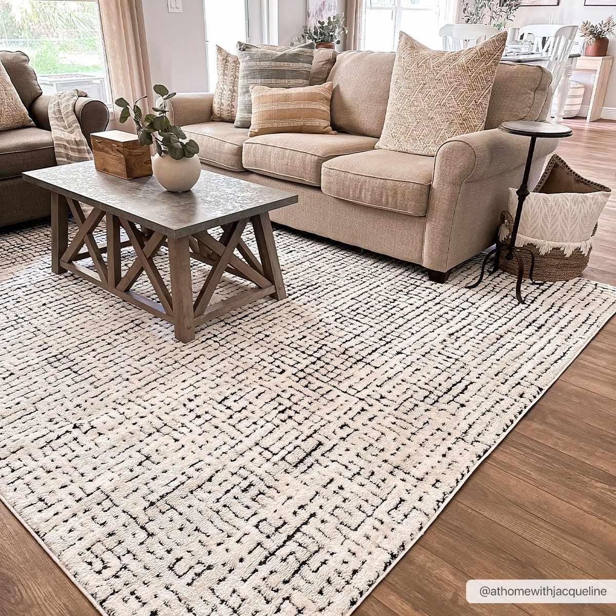 Cozy farmhouse living room with beige sofa, patterned rug, and rustic coffee table