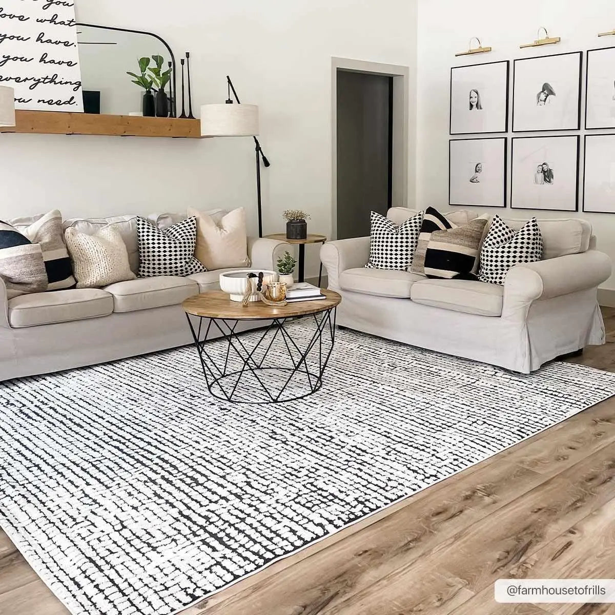 Cozy farmhouse living room with neutral sofas, patterned pillows, and black-and-white rug