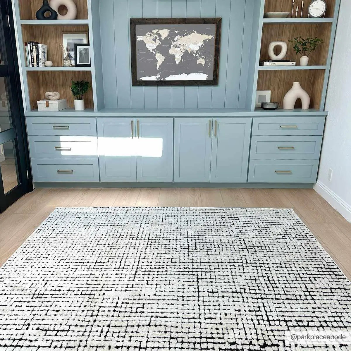 Cozy farmhouse living room with light blue built-in shelves, world map art, and black and white patterned rug