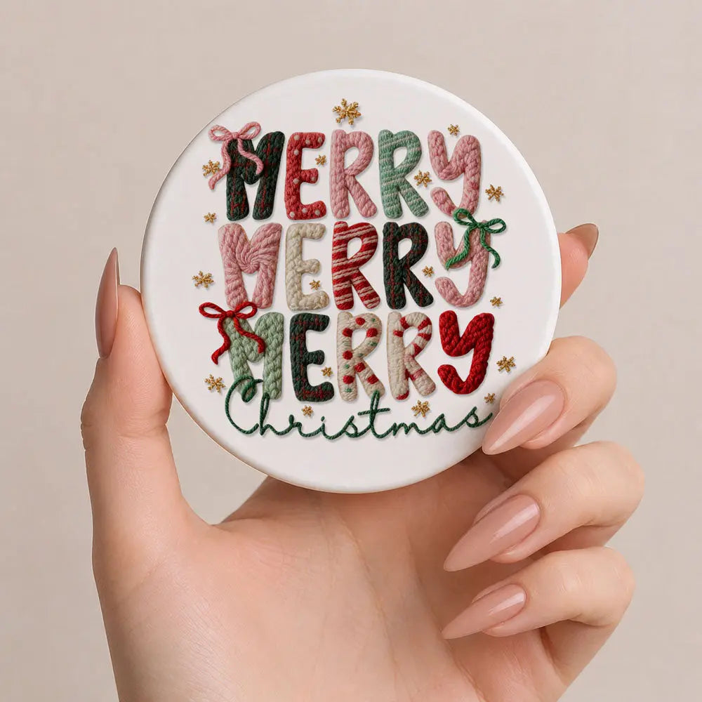 Round embroidered coaster with 'Merry Christmas' text held by a hand against a beige background