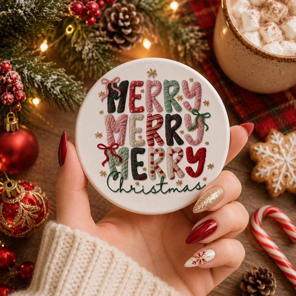 Hand holding a round white coaster with 'Merry Christmas' text, surrounded by holiday decorations.