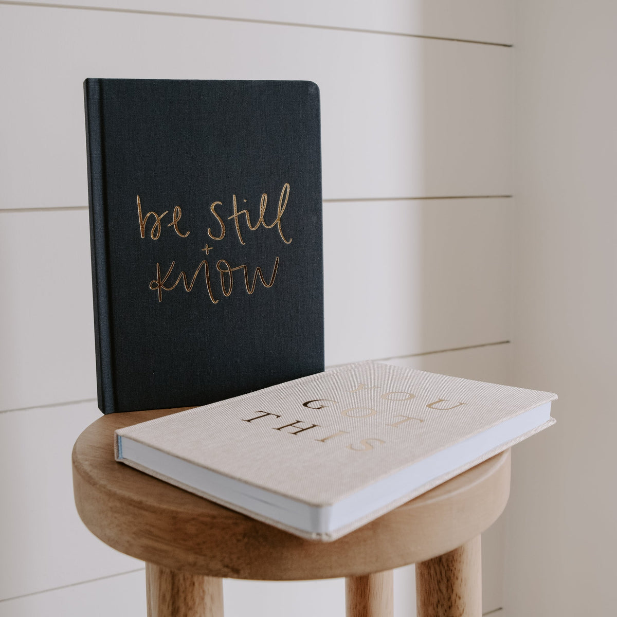 Two books on a wooden stool with motivational text on a neutral background