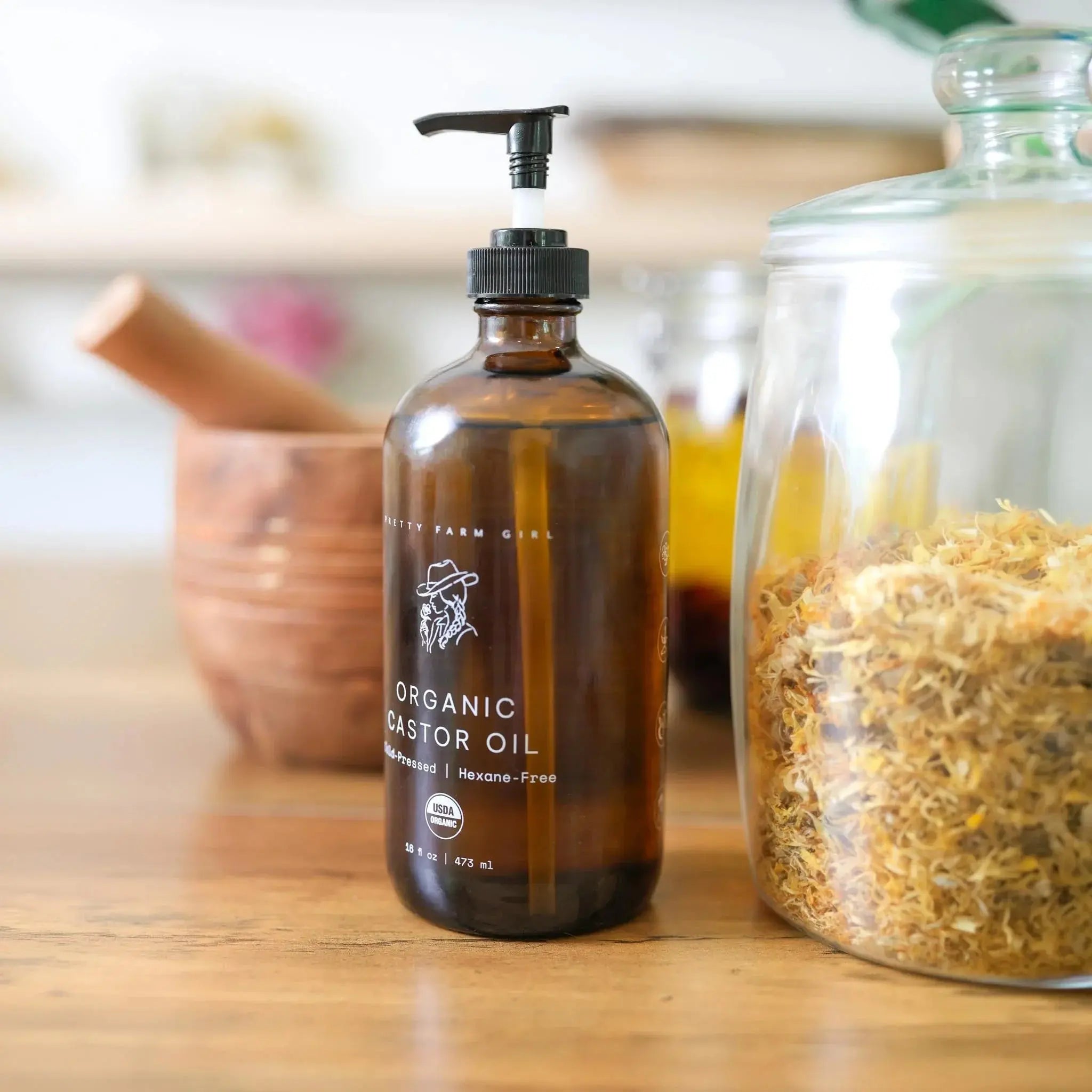 Organic castor oil in amber pump bottle with dried herbs, farmhouse bath essentials