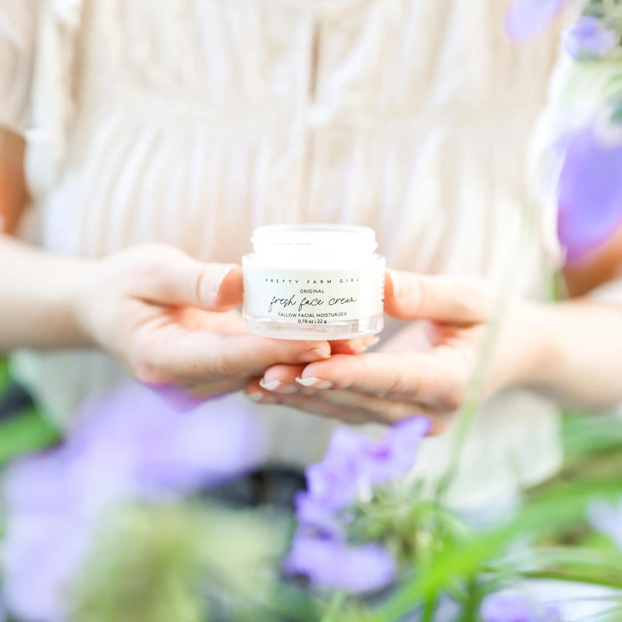 Pretty Farm Girl Original Fresh Face Cream - Tallow Facial Moisturizer held in hands with purple flowers