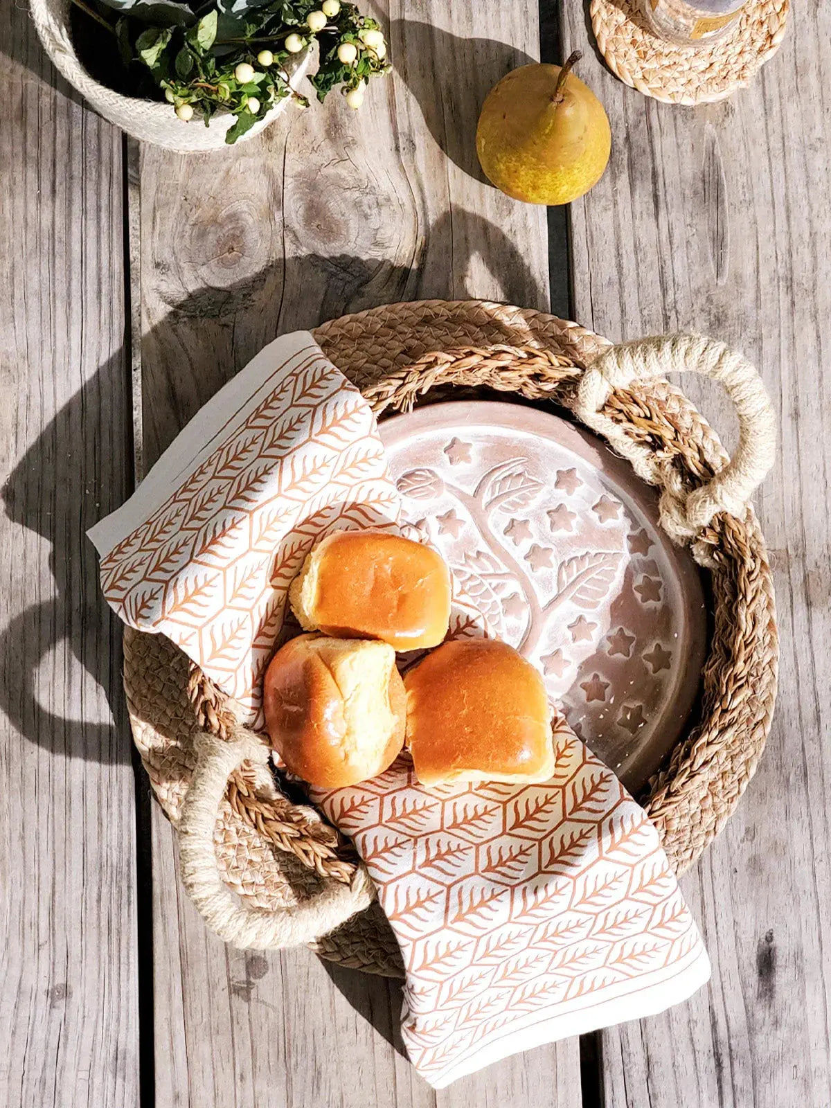 Cozy farmhouse bread basket with patterned napkin, fresh rolls, and rustic wooden table decor