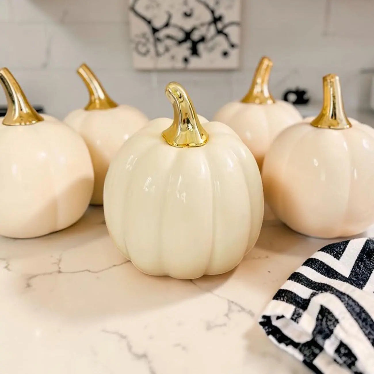 Decorative pumpkins with gold stems on a marble surface