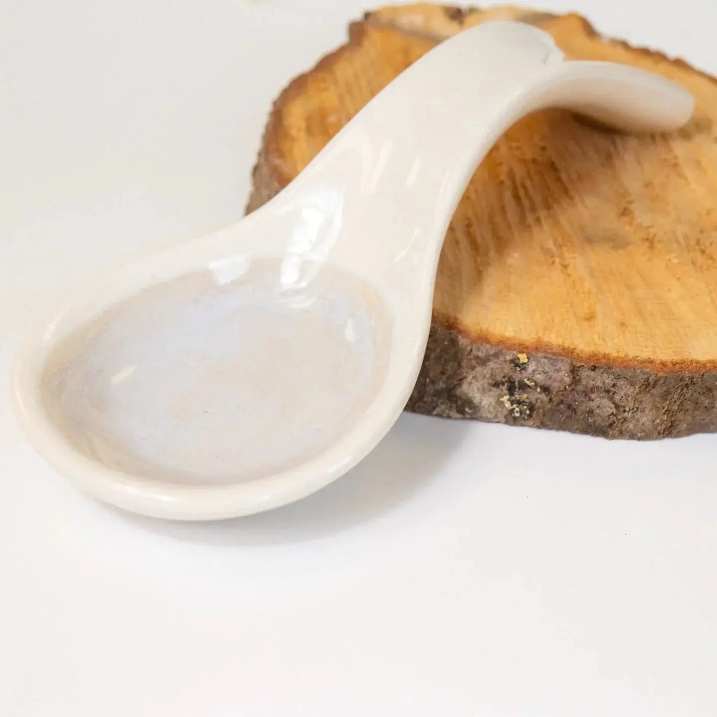 White ceramic spoon rest on rustic wood slice, farmhouse kitchen decor