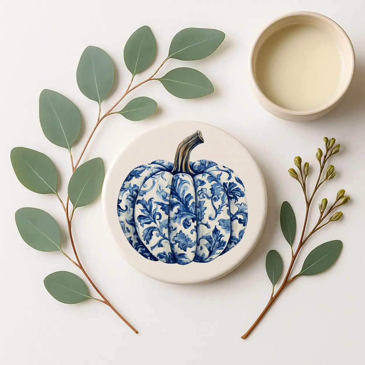 Ceramic plate with blue floral design on a white surface with green leaves