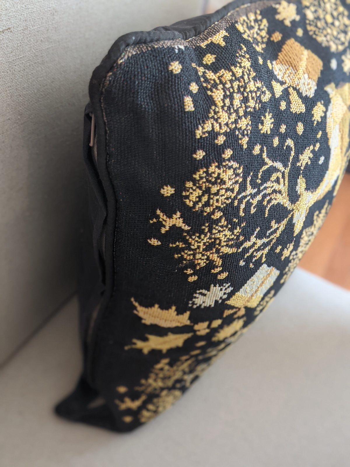 Black pouch with gold floral patterns on a light gray surface