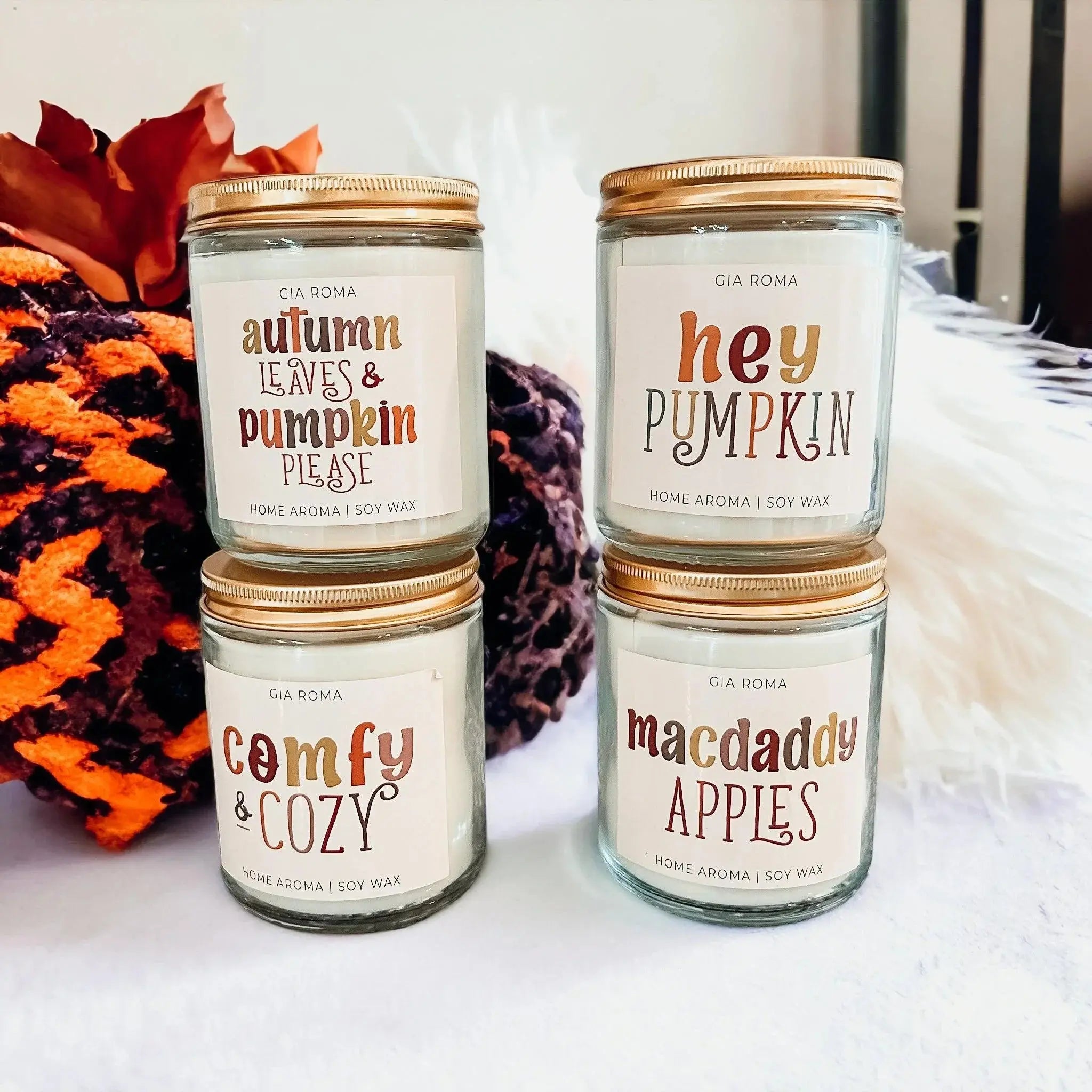 Four candles with labels on a white surface with decorative elements.