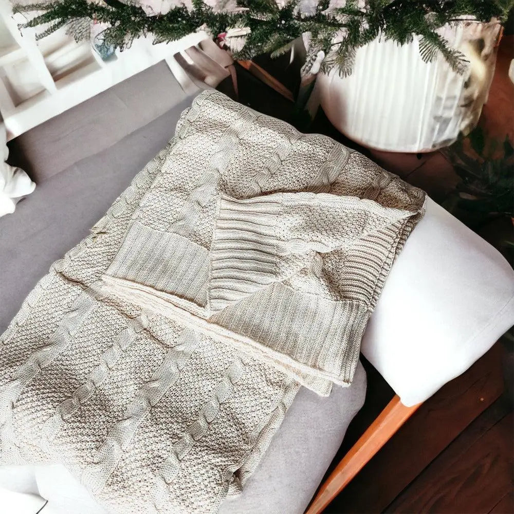 Cozy cable knit blanket draped on a farmhouse-style chair with greenery overhead