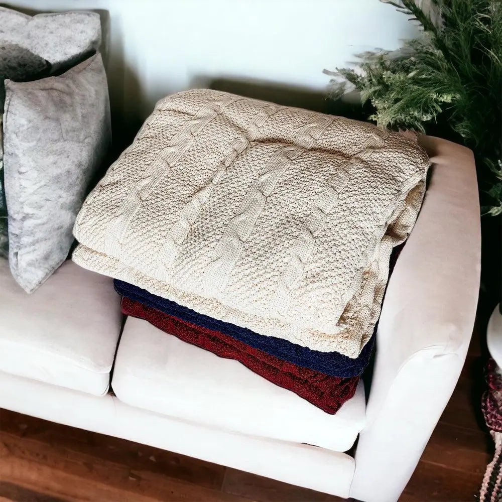Cozy cable knit blankets in cream, navy, and burgundy on a white sofa for farmhouse decor