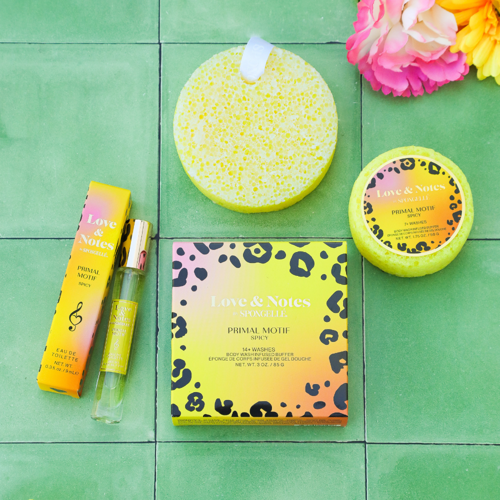 Collection of 'Love & Notes' products including a sponge, box, and bottle on a green tiled background with flowers.