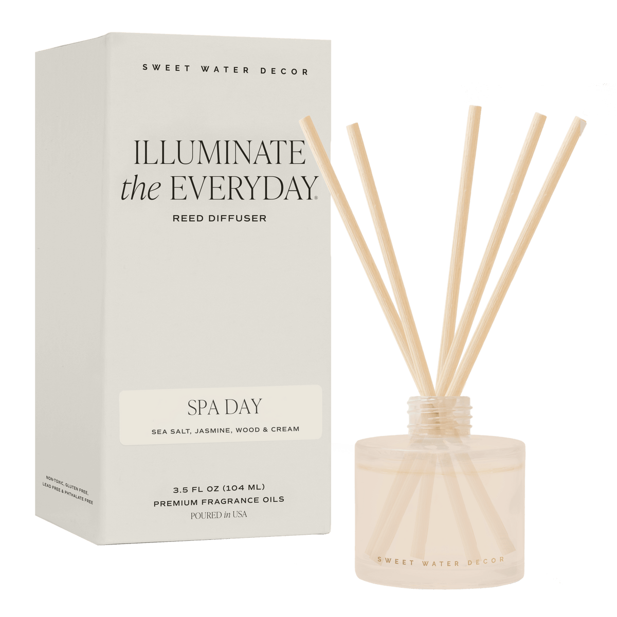 A reed diffuser set with a white box labeled 'Illuminate the Everyday' and 'Spa Day' by Sweet Water Decor, alongside a clear glass bottle filled with pale fragrance oil and natural reed sticks, shown on a solid green background.