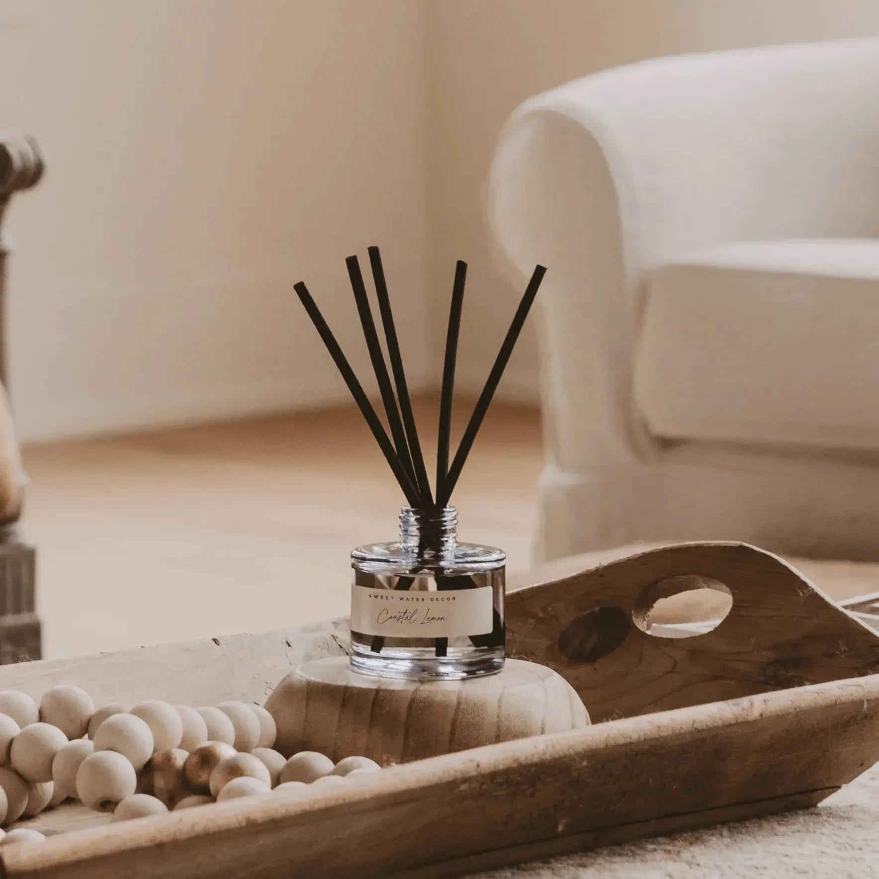 Coastal Lemon reed diffuser on wooden tray, cozy farmhouse home decor with wooden beads and soft lighting