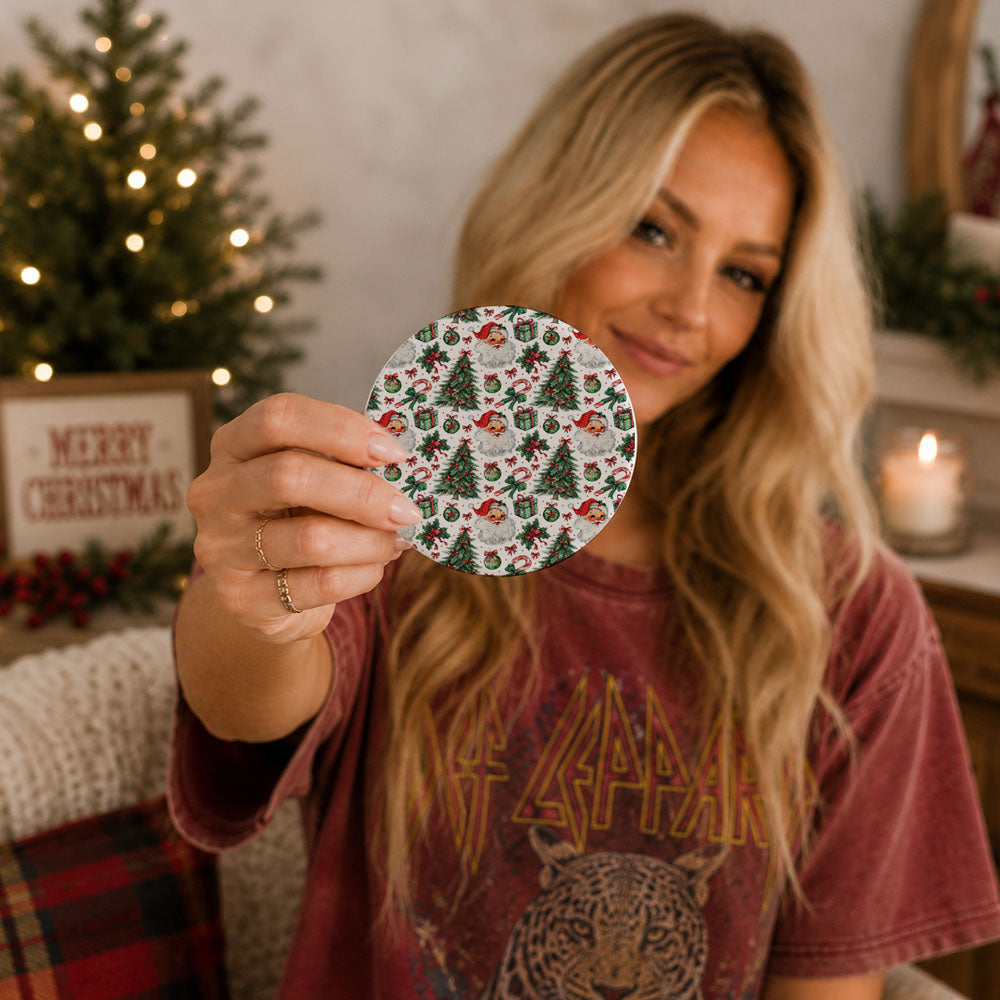 Woman holding a Christmas-themed coaster in front of a decorated Christmas tree.