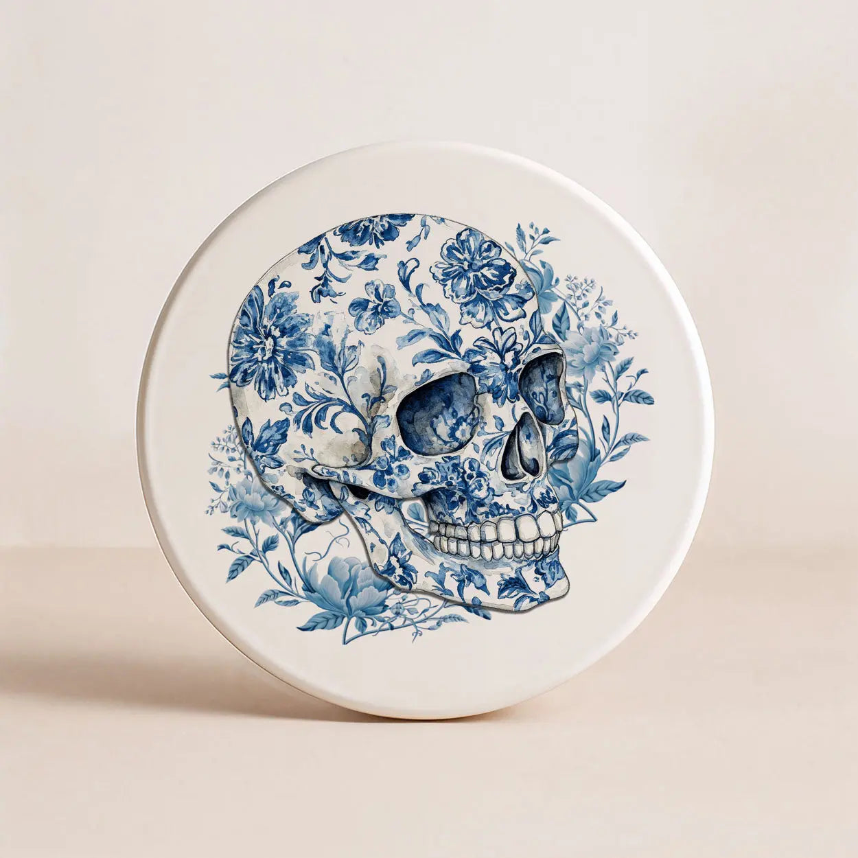 Decorative plate with a blue floral skull design on a beige background