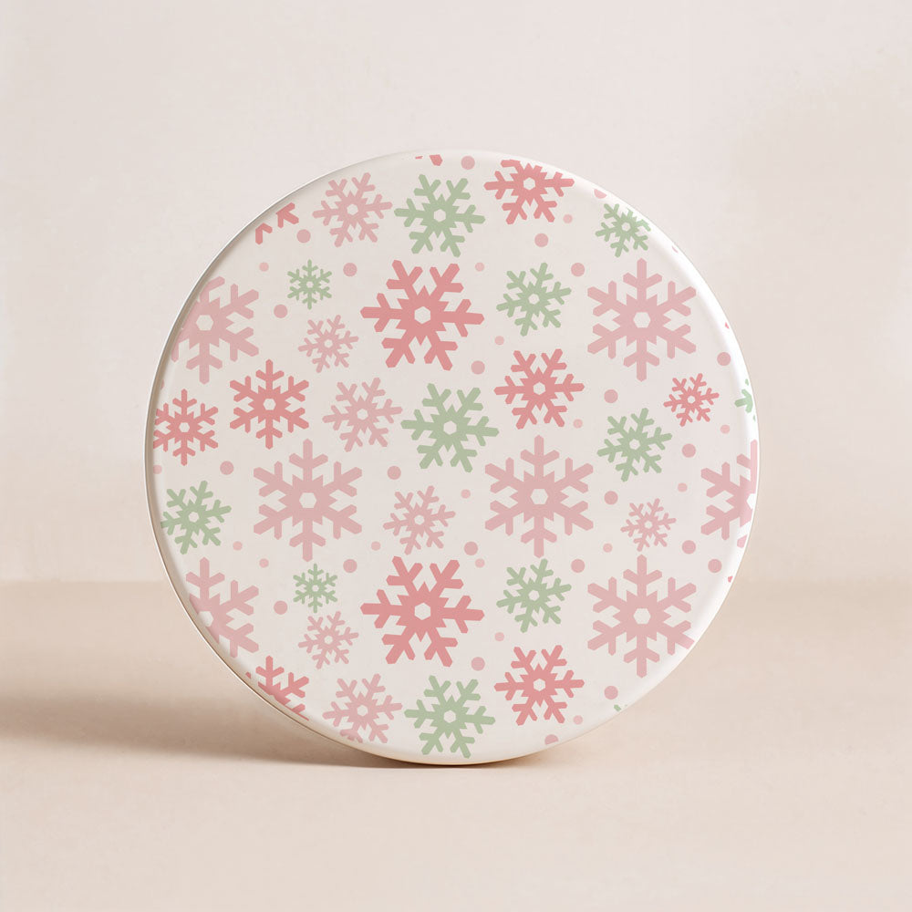Round ceramic plate with pink and green snowflake pattern on a beige background