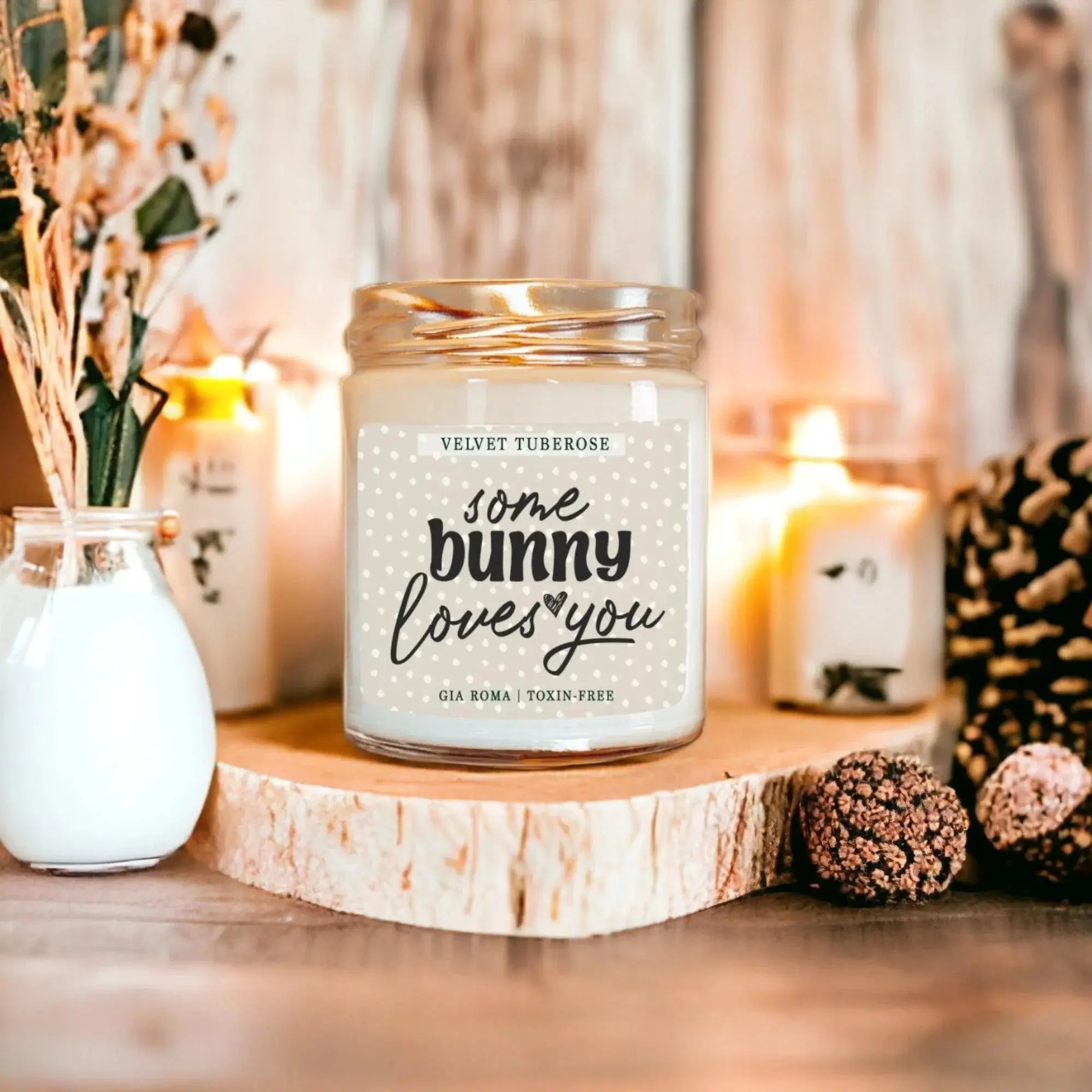 Candle with 'some bunny loves you' label on a wooden surface with decorative elements.