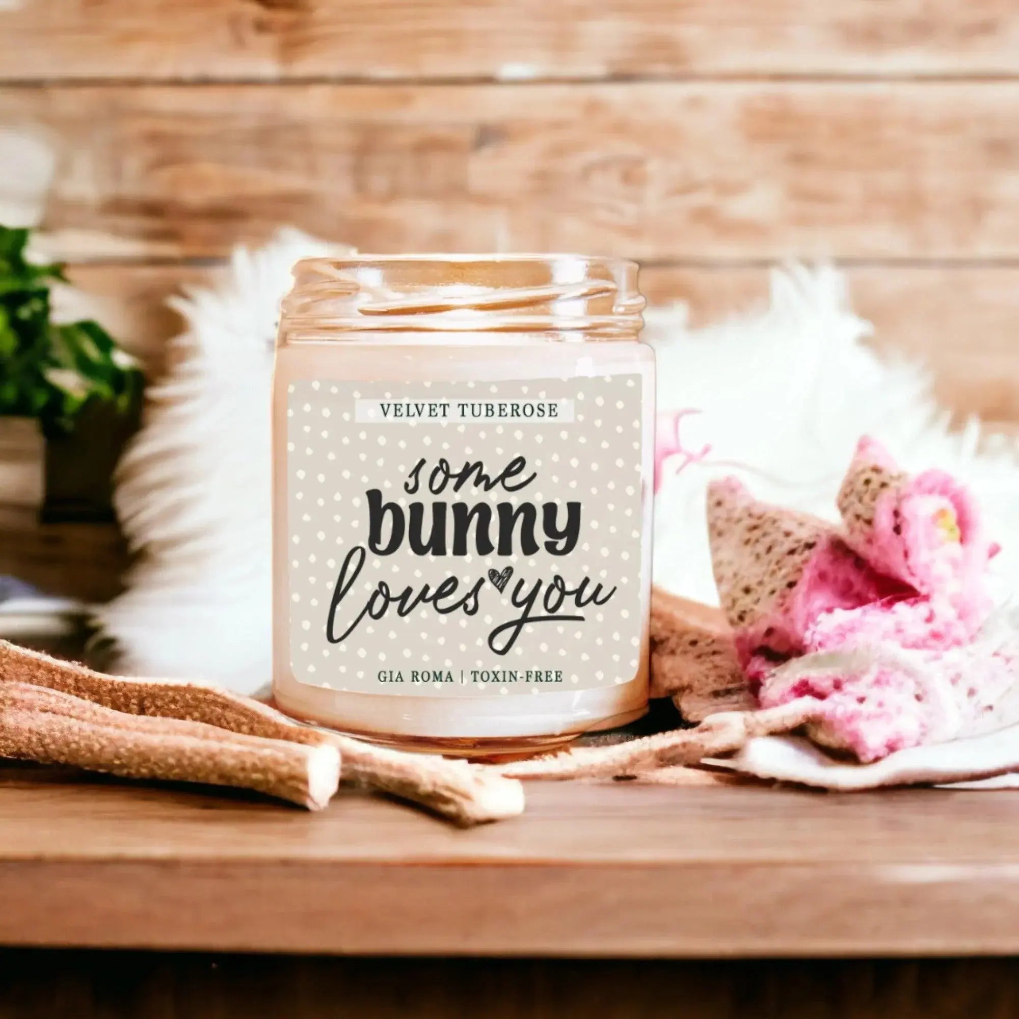 Candle jar with 'some bunny loves you' text on a wooden surface