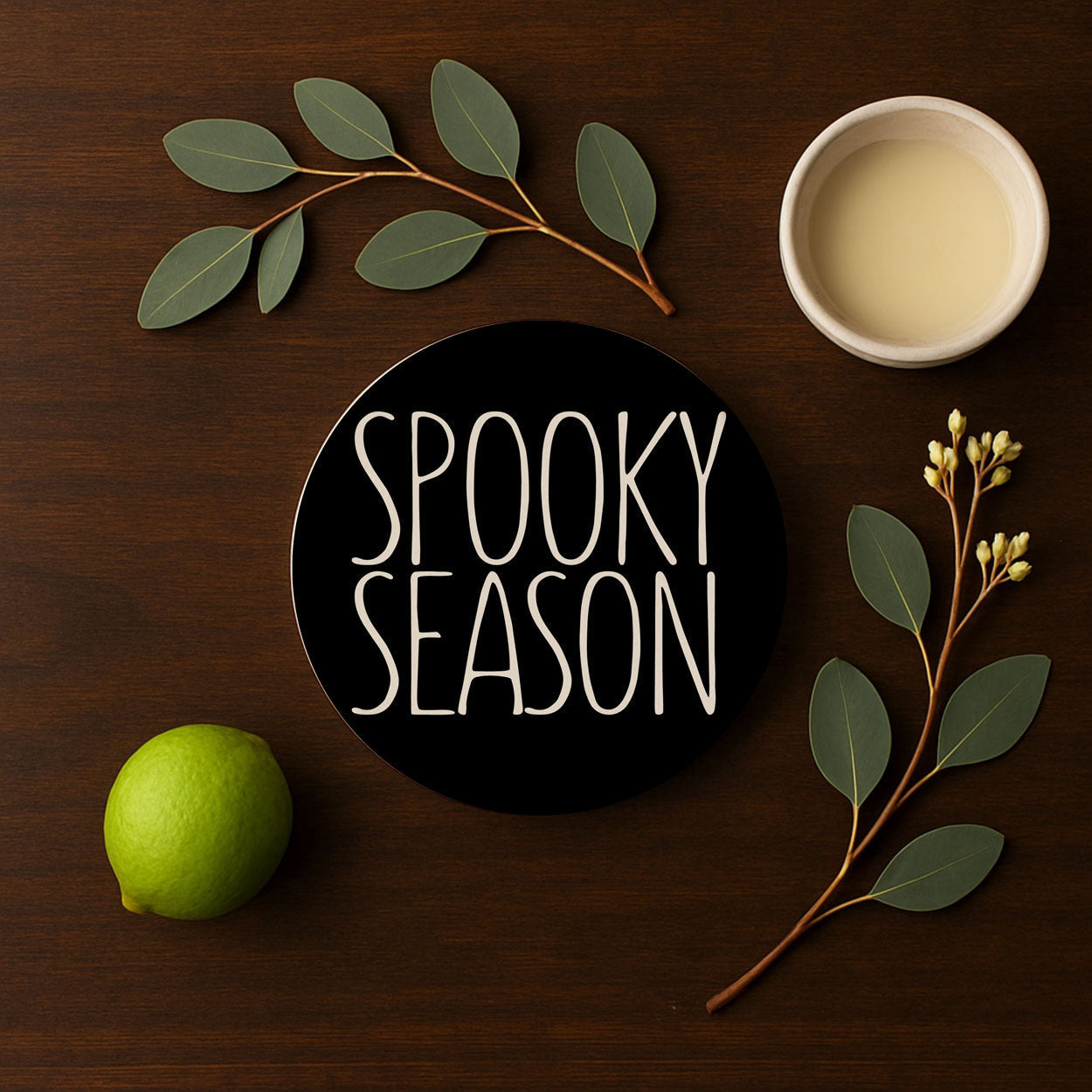 Decorative sign with 'Spooky Season' text on a wooden surface with leaves and a lime.