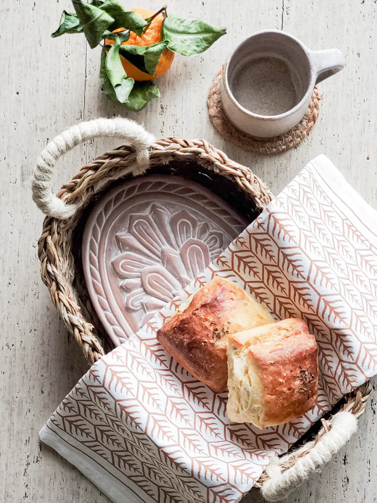 Cozy farmhouse breakfast with woven basket, patterned napkin, ceramic mug, and fresh bread on rustic wood