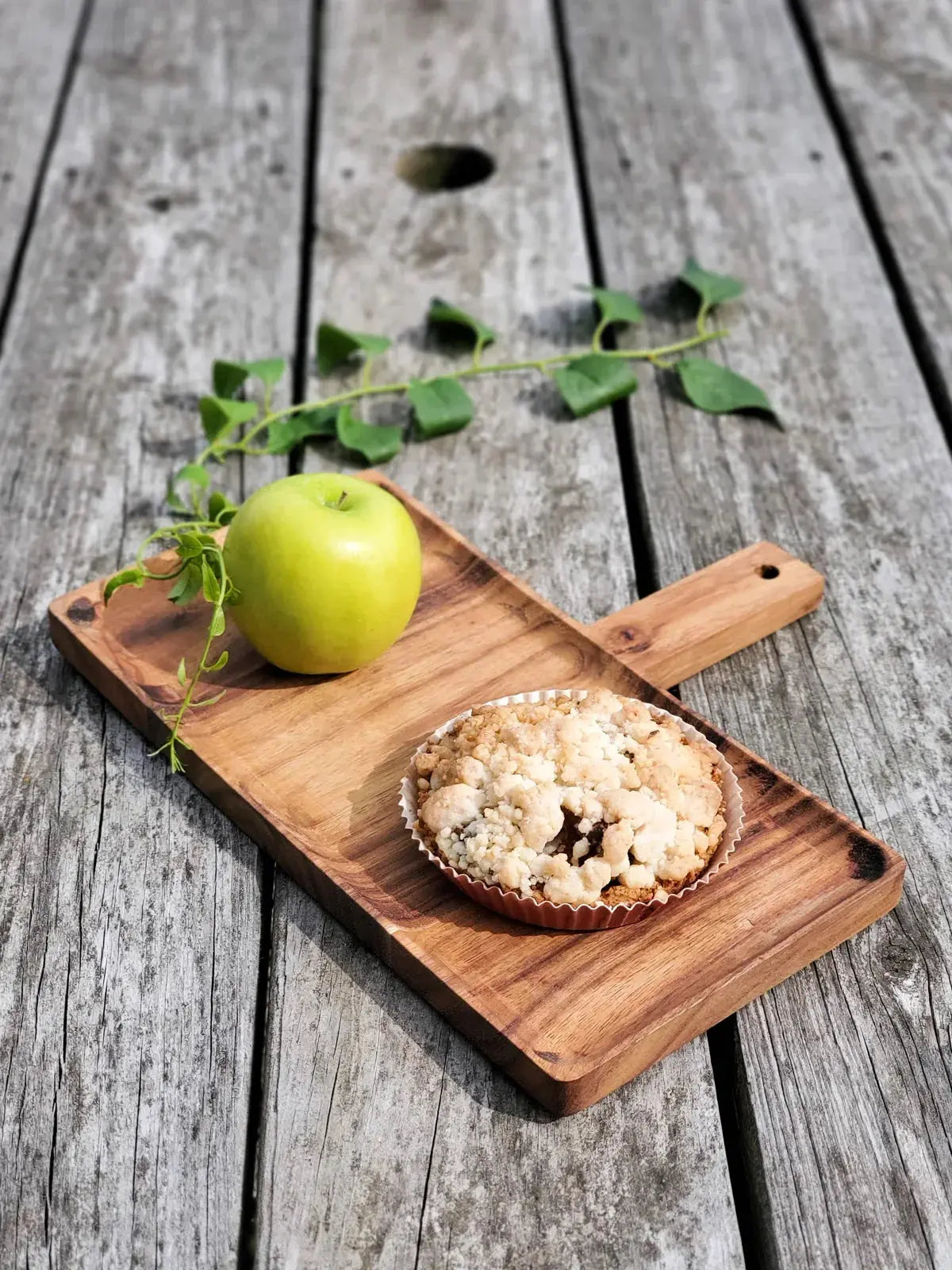 Apple crumble dessert with fresh green apple on rustic wooden board, farmhouse style
