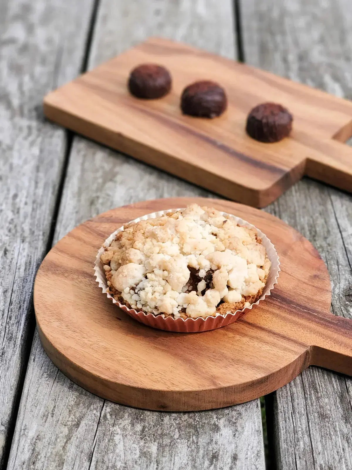 Cozy farmhouse-style crumble tartlet on wooden board with chocolate truffles, rustic home decor