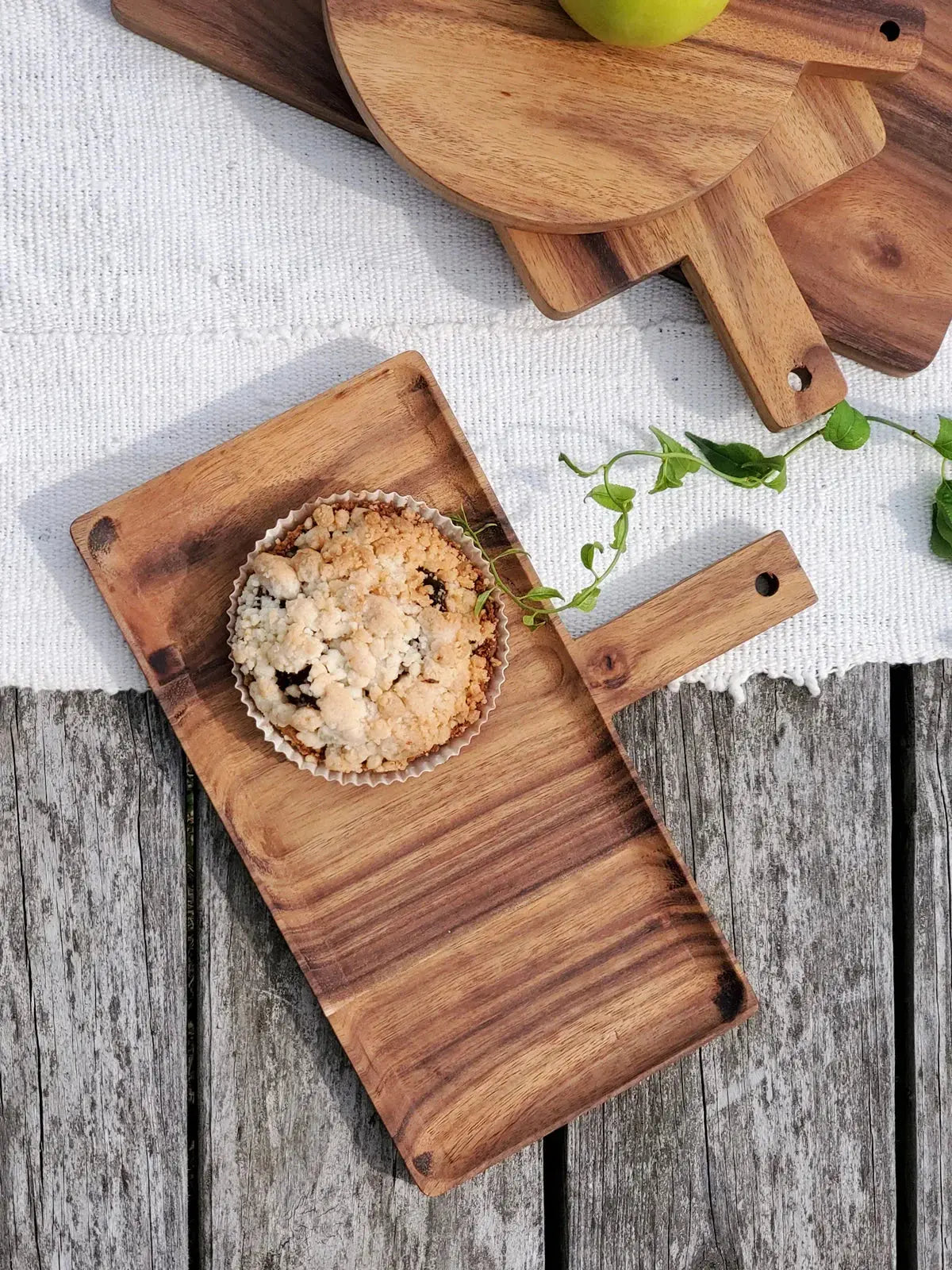 Rustic wooden serving tray with crumble tart, green apple, and fresh herbs on farmhouse table
