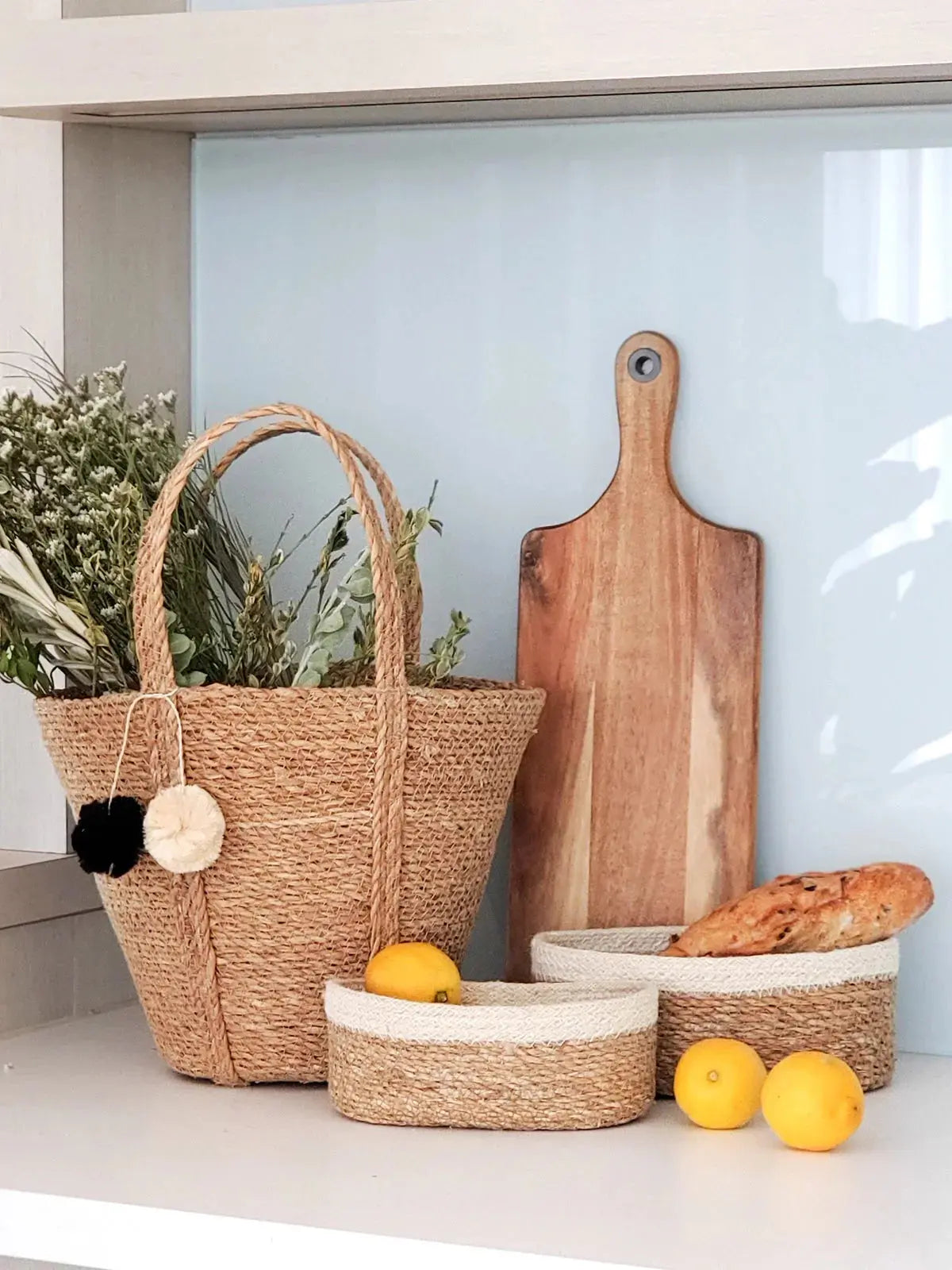 Cozy farmhouse kitchen decor with woven baskets, wooden cutting board, lemons, and dried flowers on shelf