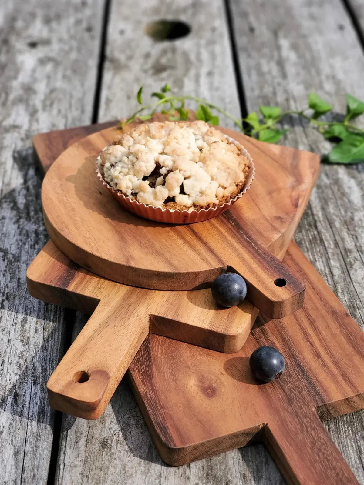 Blueberry crumble pie on rustic wooden cutting boards with fresh berries and greenery, farmhouse kitchen decor