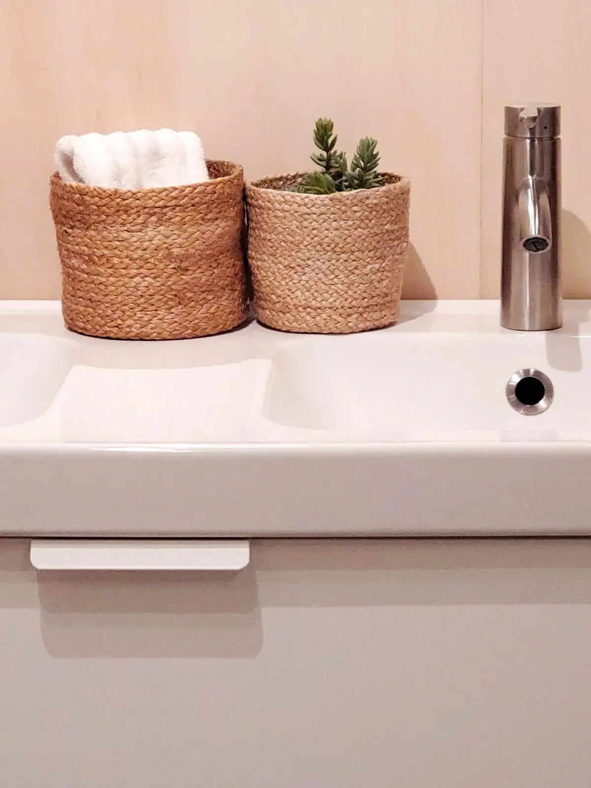 Woven seagrass baskets with white towel and succulent on bathroom sink, cozy farmhouse decor
