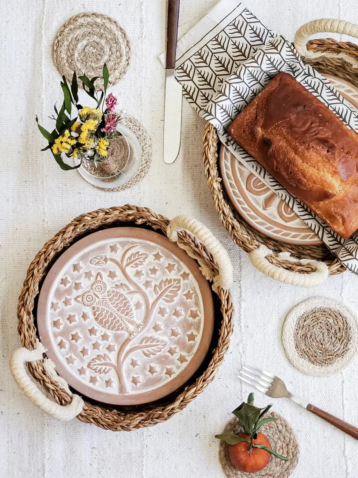 Cozy farmhouse table setting with woven trays, owl plate, bread, and floral accents for rustic home decor