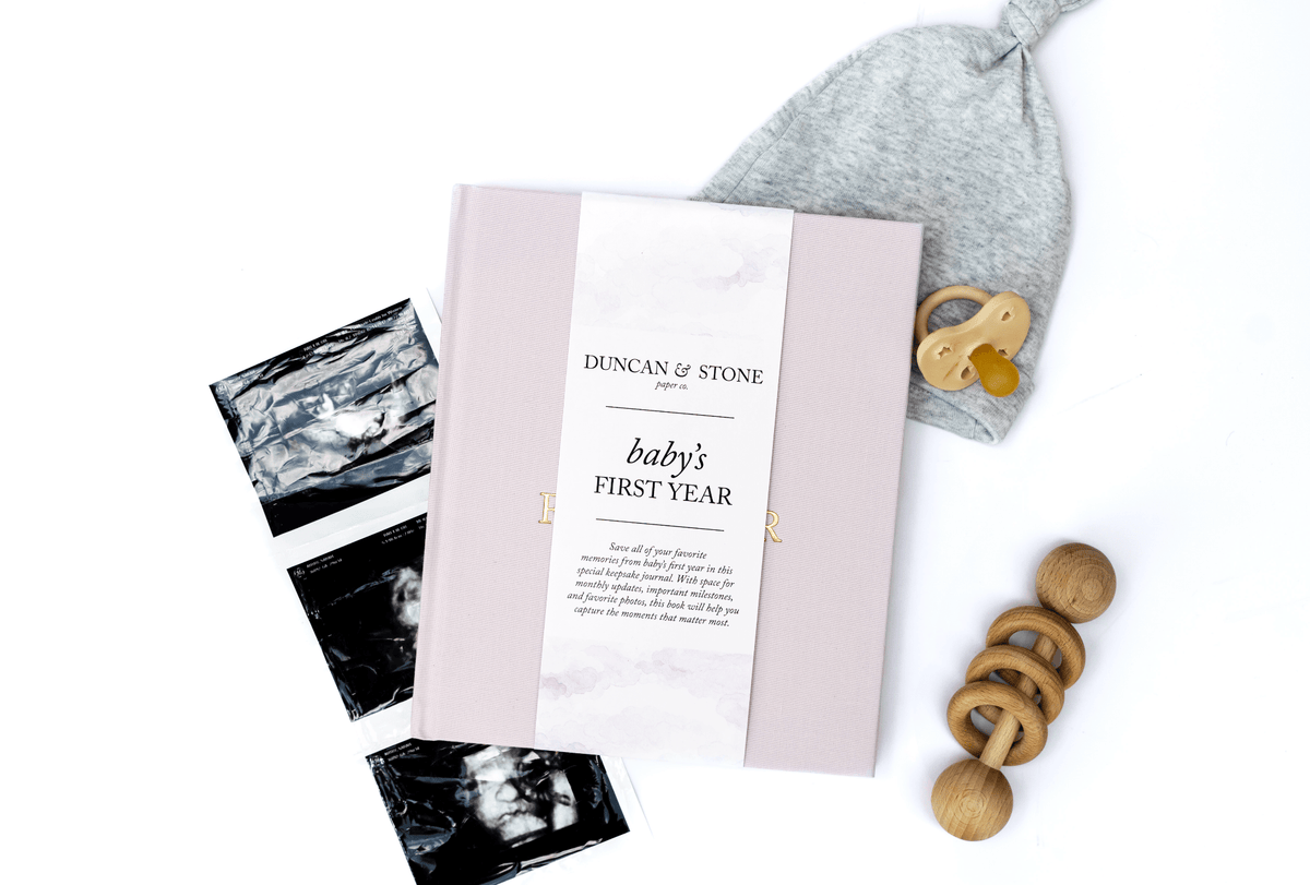 Baby milestone cards, hat, and wooden ring on a white background