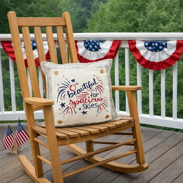 Wooden rocking chair with a decorative pillow on a deck, surrounded by American flags and bunting.
