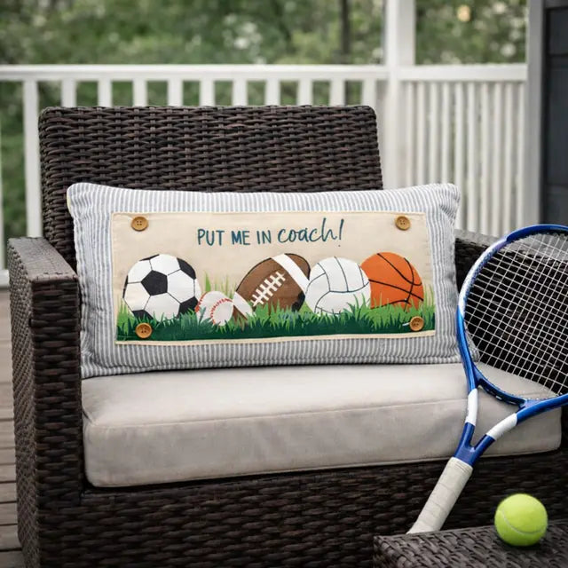 Decorative pillow with sports ball illustrations on a wicker chair outdoors.