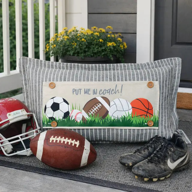 Decorative pillow with sports-themed design on a porch with sports equipment.