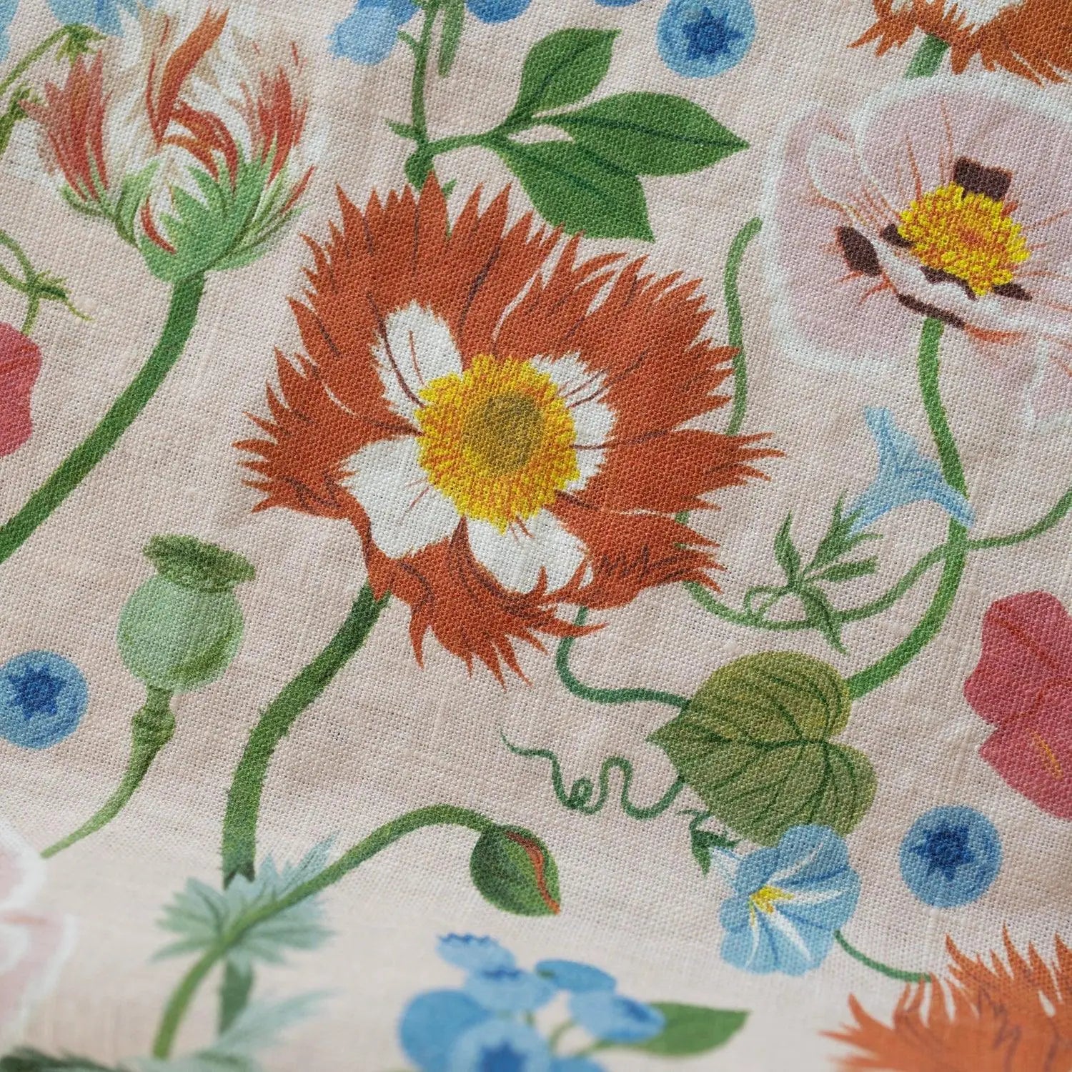 Close-up of floral fabric with red, yellow, and blue flowers on a beige background