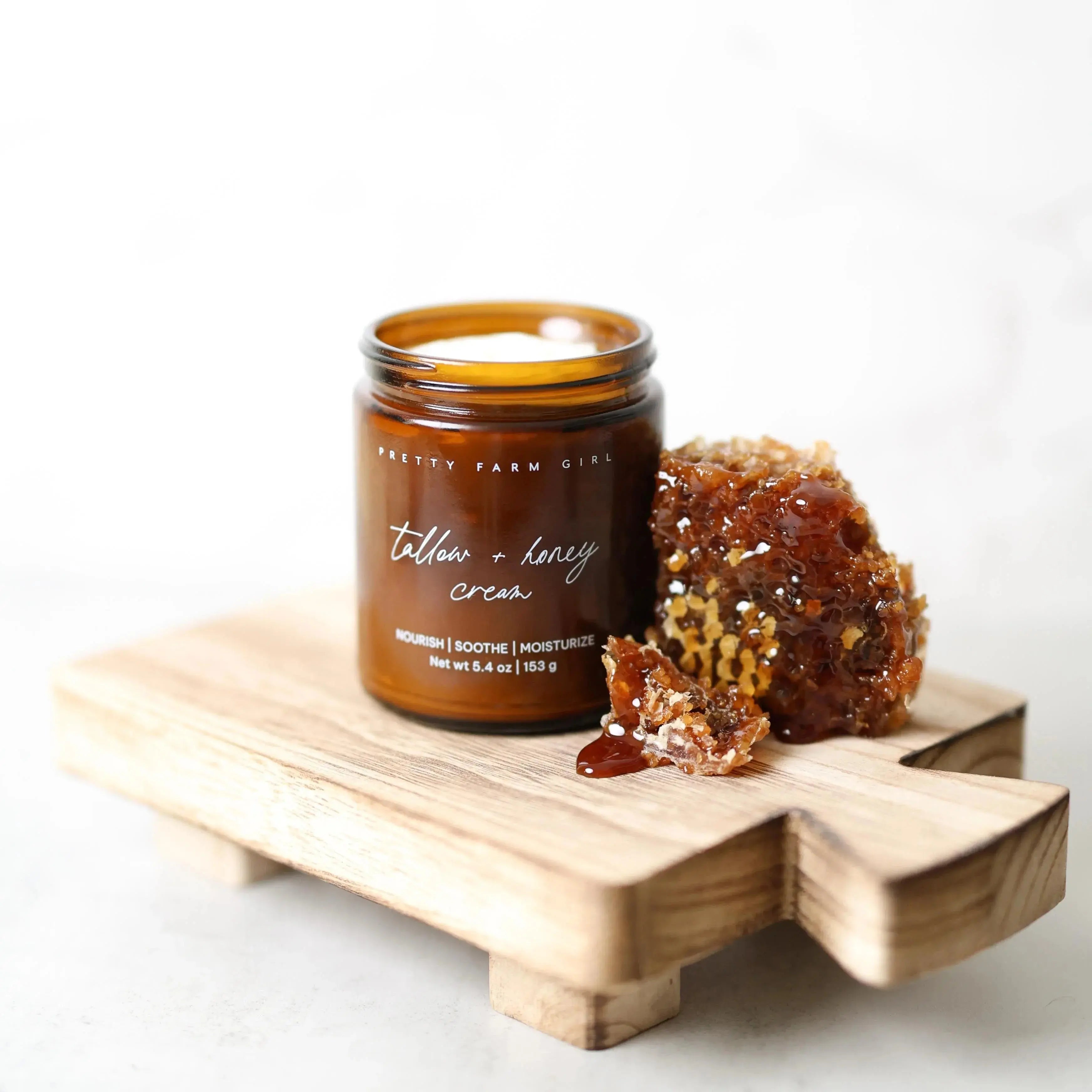 Tallow + honey cream in amber jar with honeycomb on wooden tray, cozy farmhouse skincare