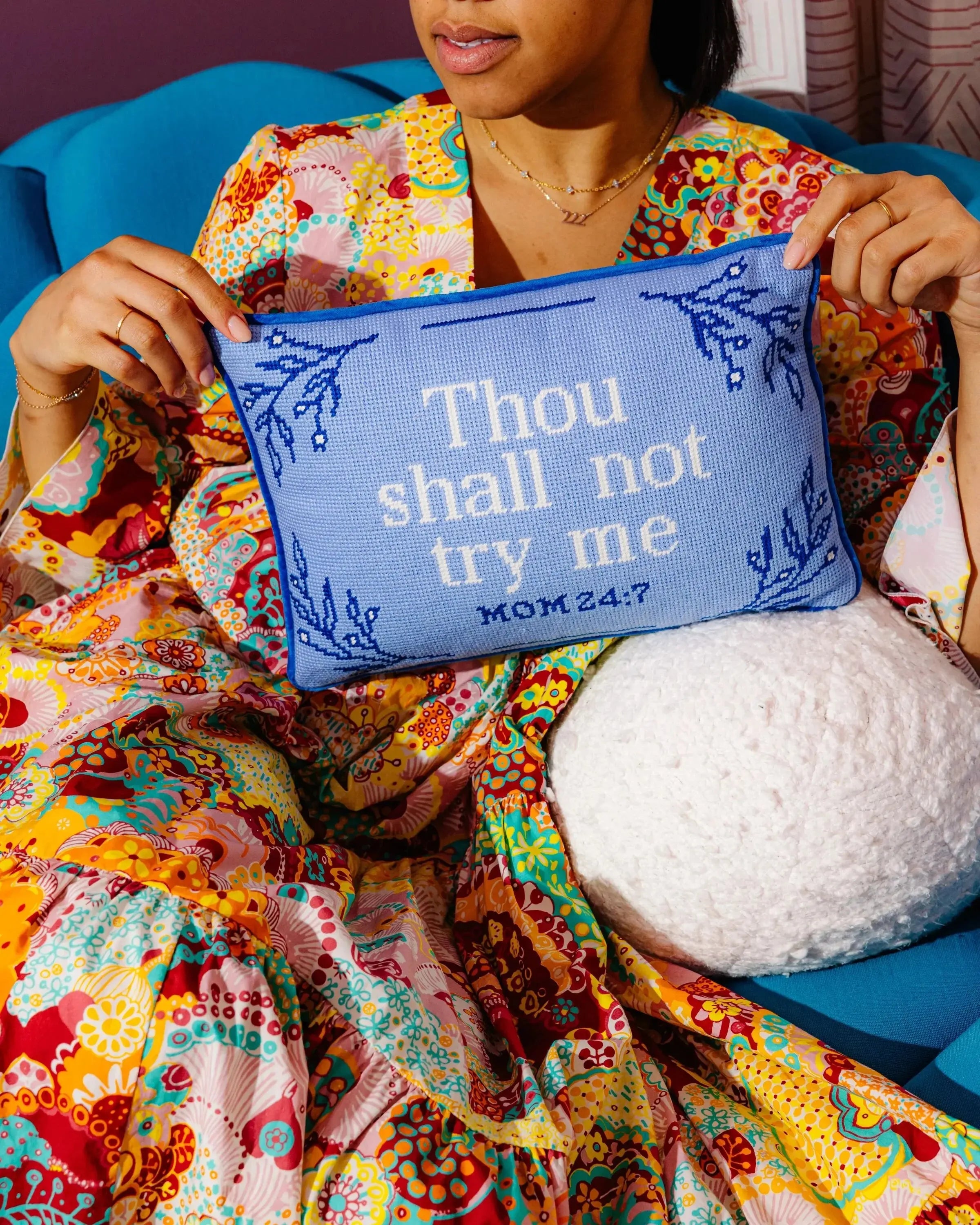 Cozy blue needlepoint pillow with 'Thou shall not try me MOM 24:7' text, held by woman in colorful robe, farmhouse decor style