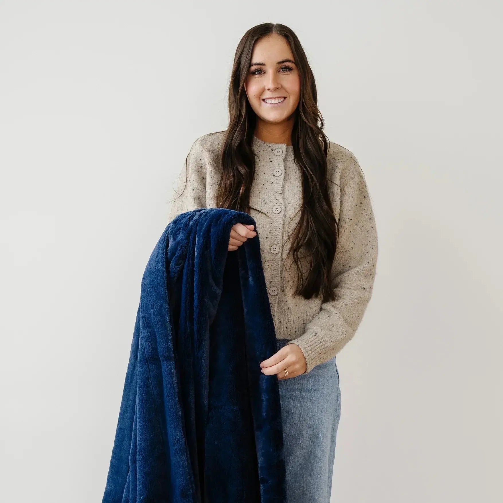 Woman holding a blue blanket against a plain background