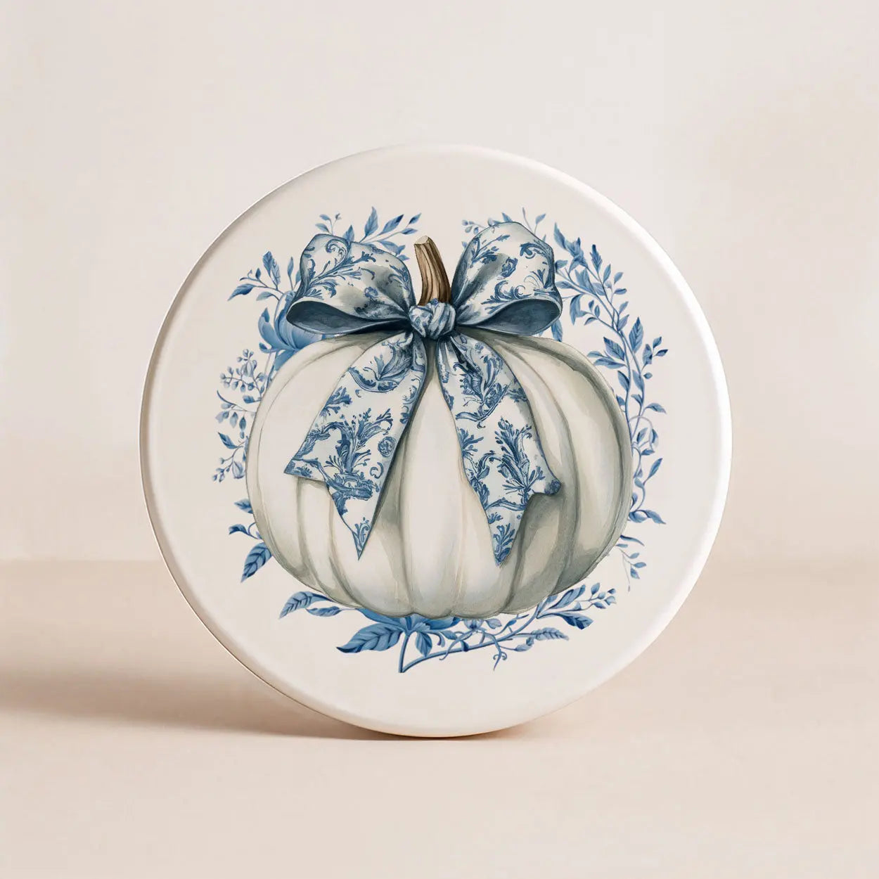 Decorative plate with a white pumpkin and blue floral bow on a beige background