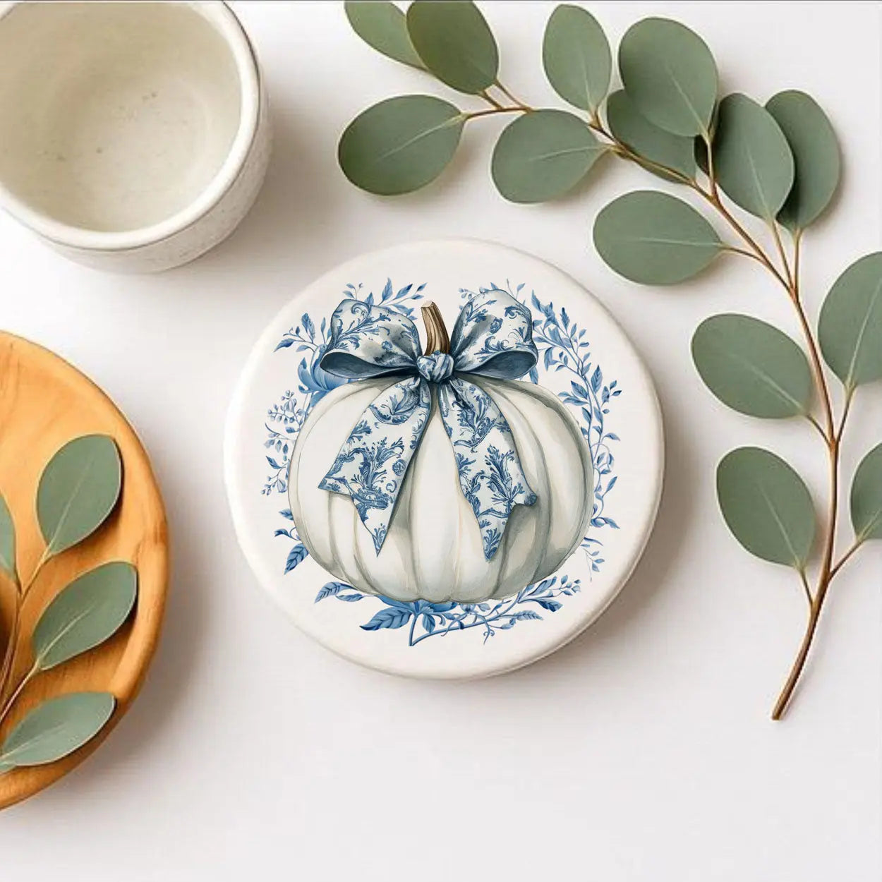 Decorative plate with blue floral design on a white surface with green leaves.